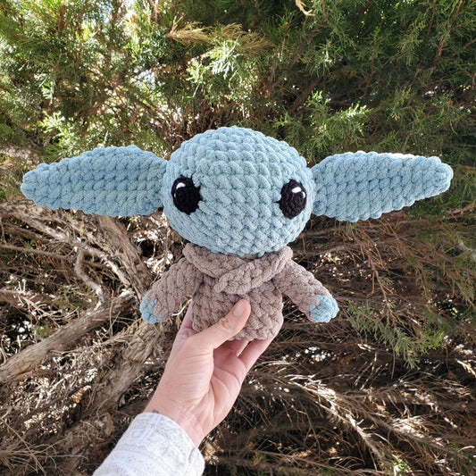 A crocheted green baby Yoda wearing a brown jacket