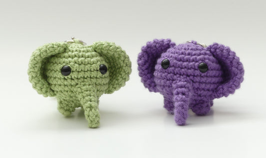 Two crocheted elephant keychains, one purple and one light green